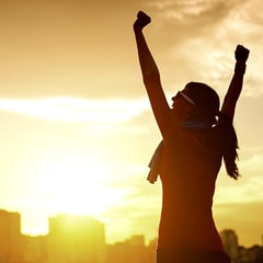 woman with arms raised and the sun shining