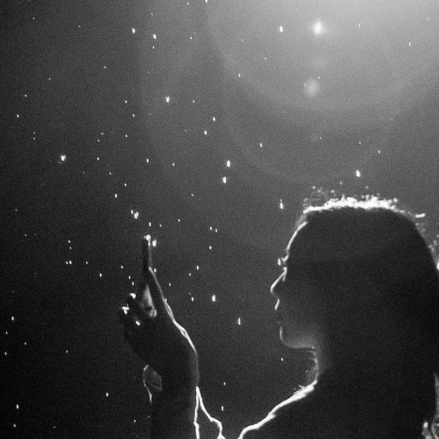 black and white of a woman holding a cell phone surrounded by glittering lights