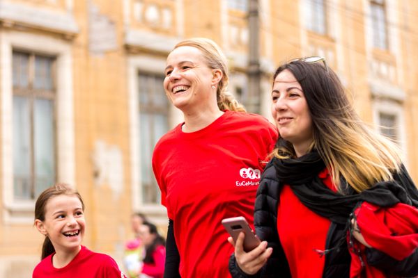 Two women and one girl in red shirts walk down the street as part of a nonprofit fundraiser.